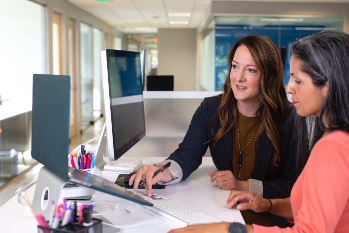 two women in office using laptop